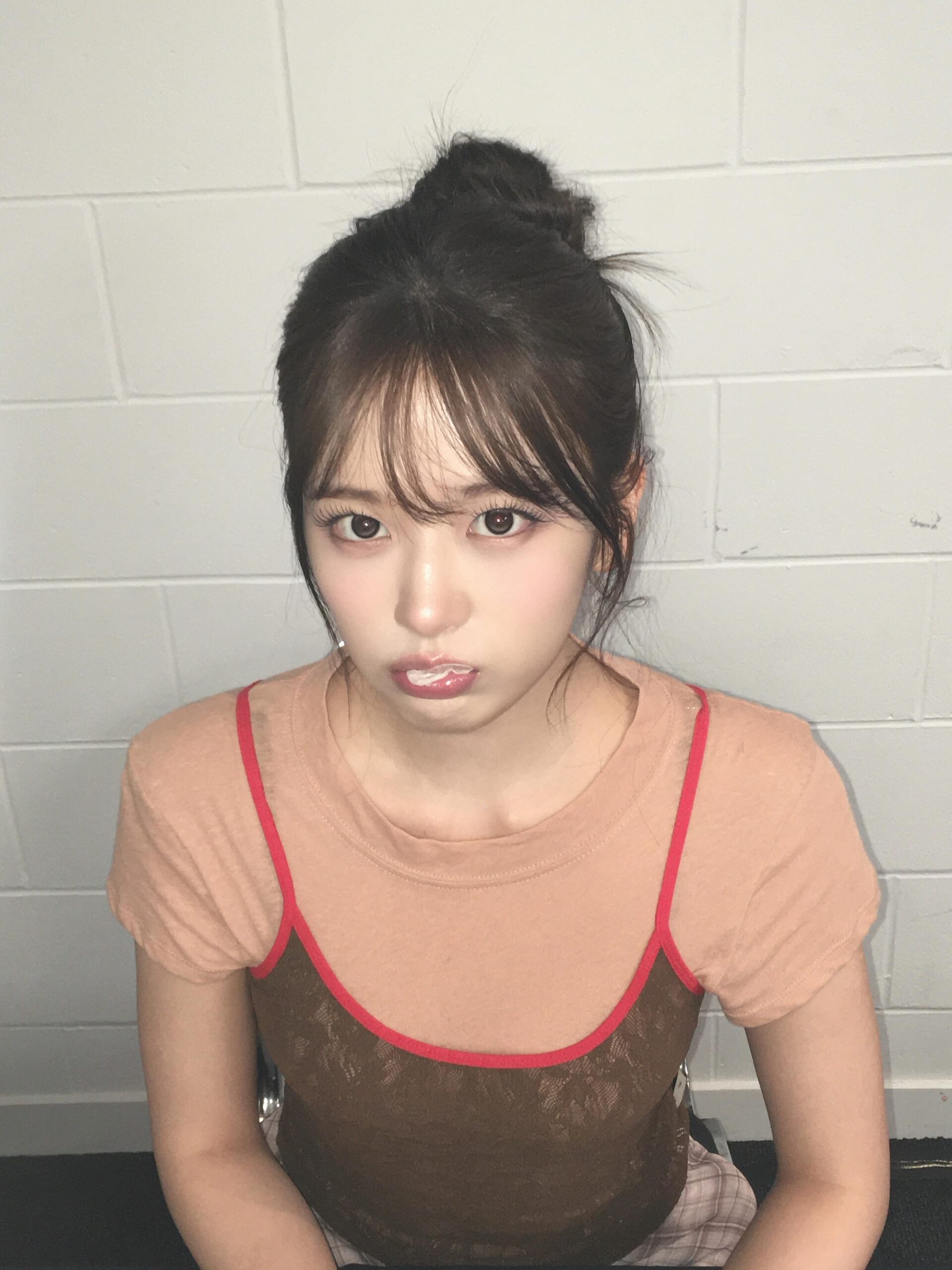 An Yujin seen with arms crossed, holding bubblegum and posing in a cute strappy camisole