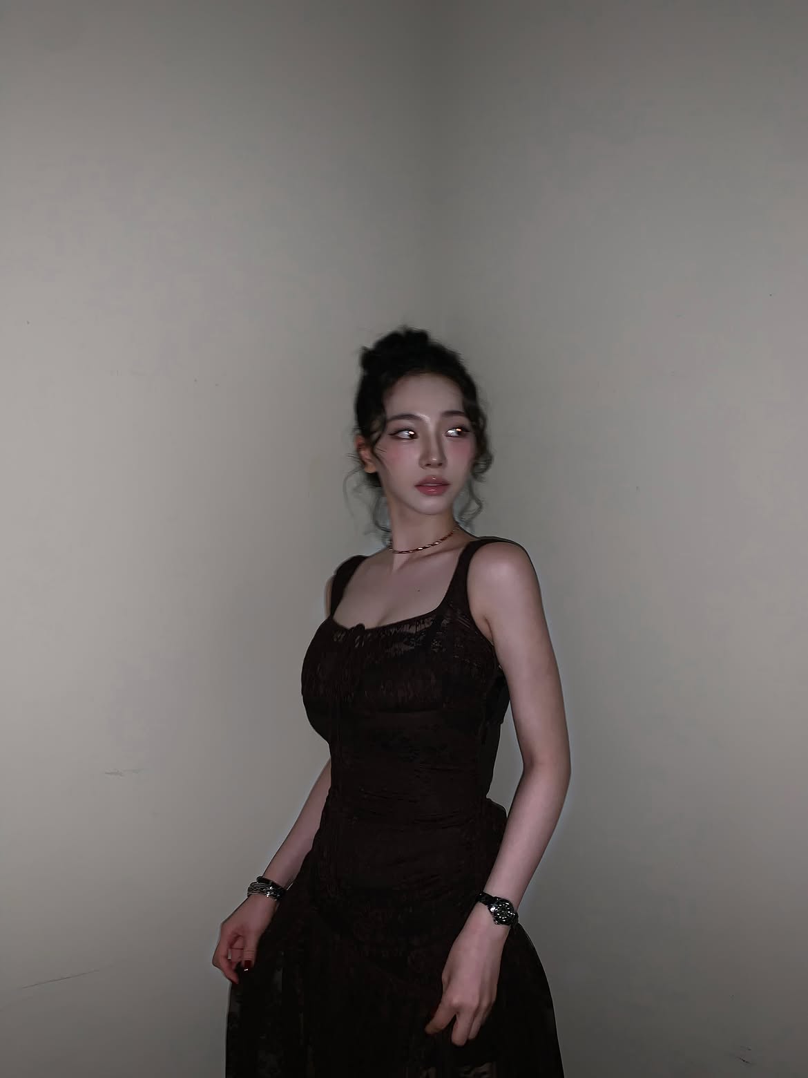 Karina in a black sheer dress crouching down, chest area - Instagram