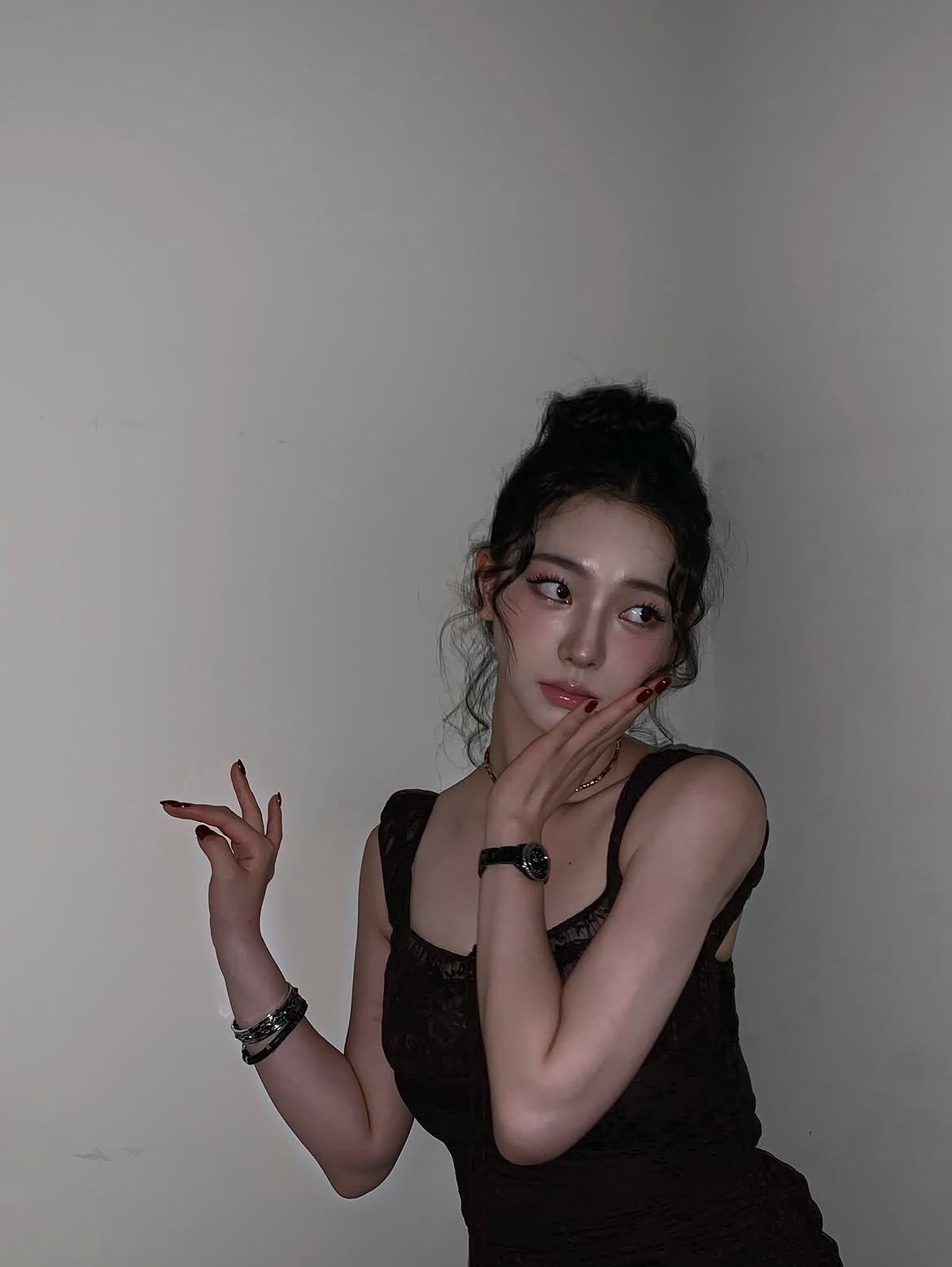 Karina in a black sheer dress crouching down, chest area - Instagram