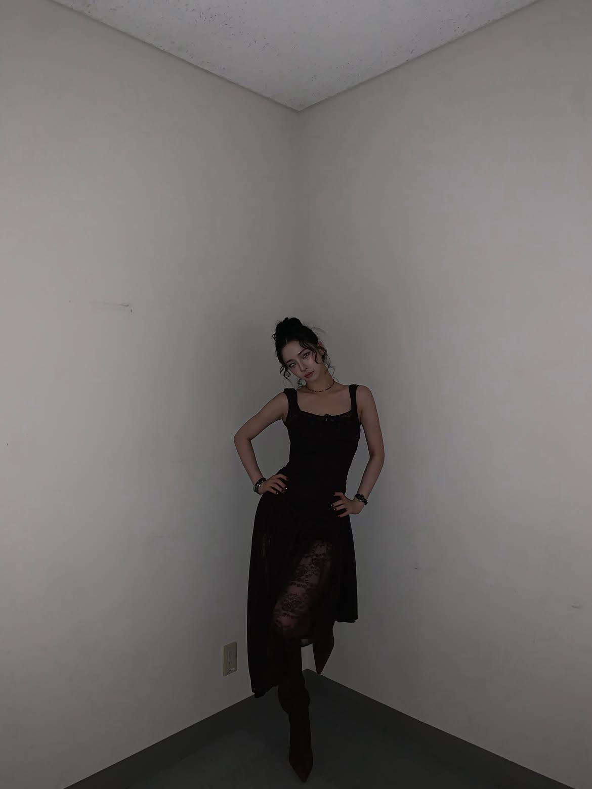 Karina in a black sheer dress crouching down, chest area - Instagram