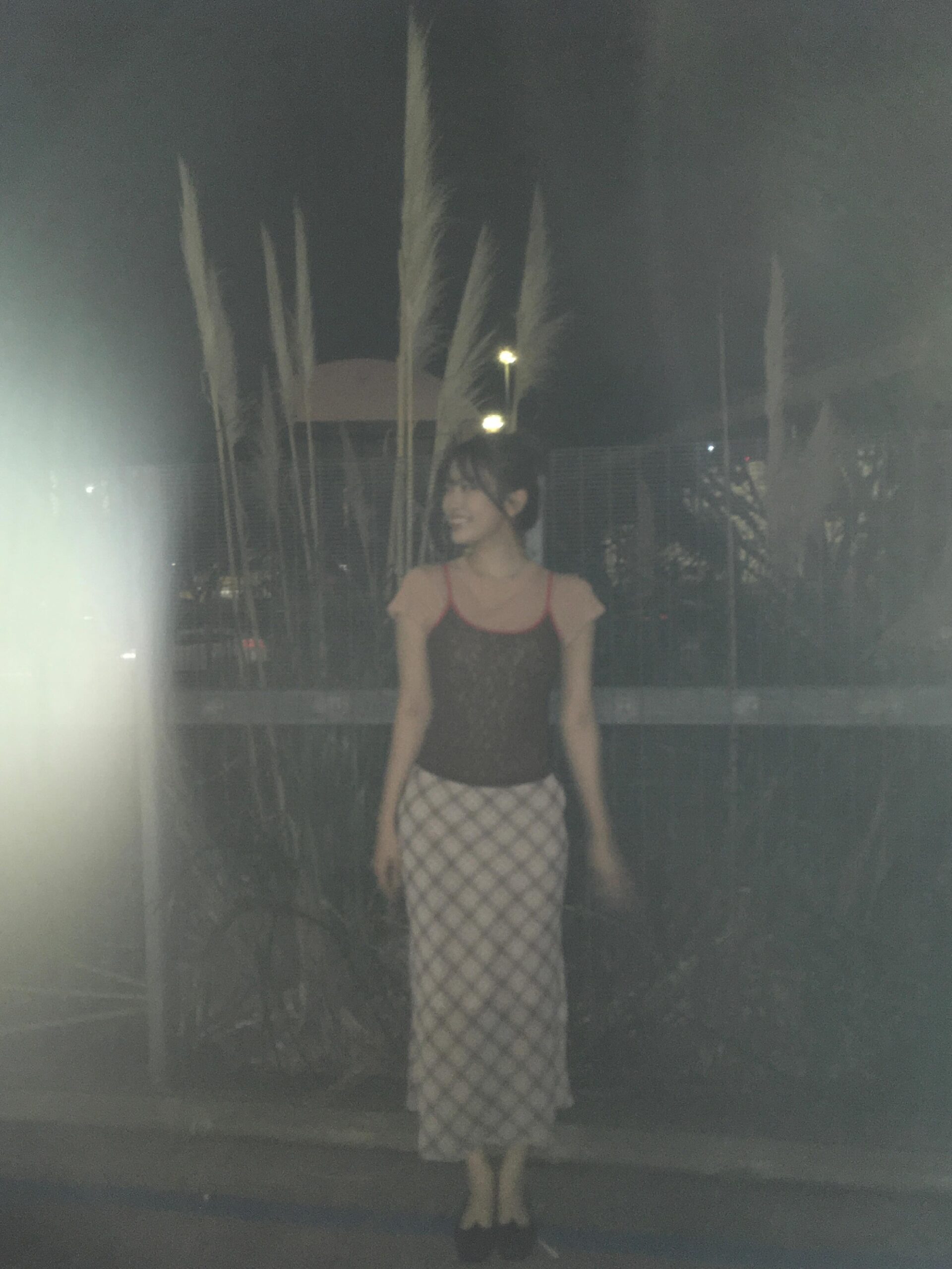 An Yujin seen with arms crossed, holding bubblegum and posing in a cute strappy camisole