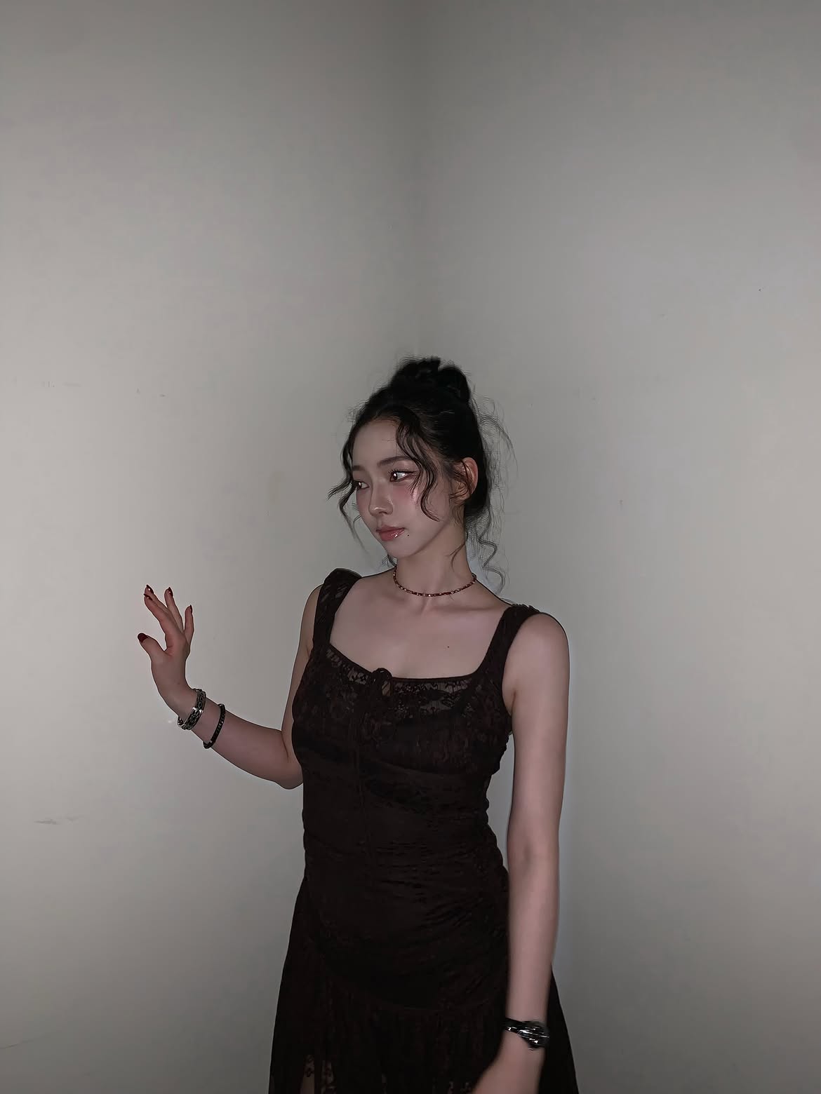 Karina in a black sheer dress crouching down, chest area - Instagram