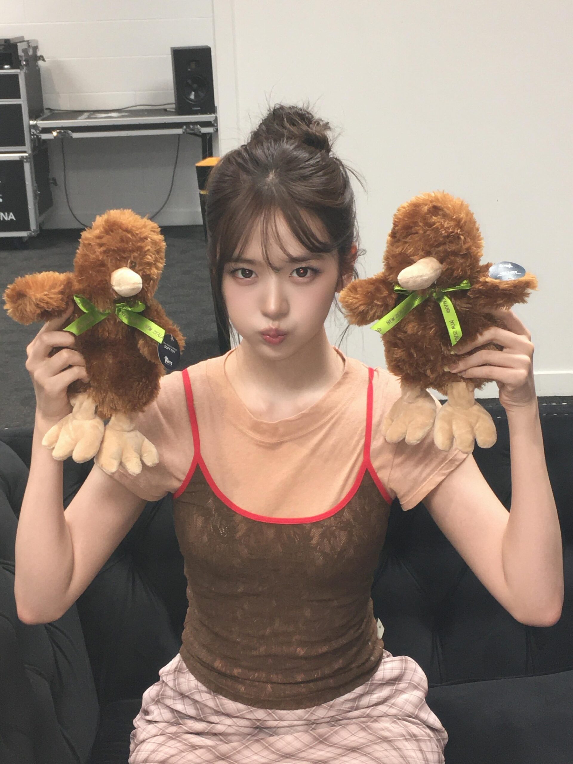 An Yujin seen with arms crossed, holding bubblegum and posing in a cute strappy camisole