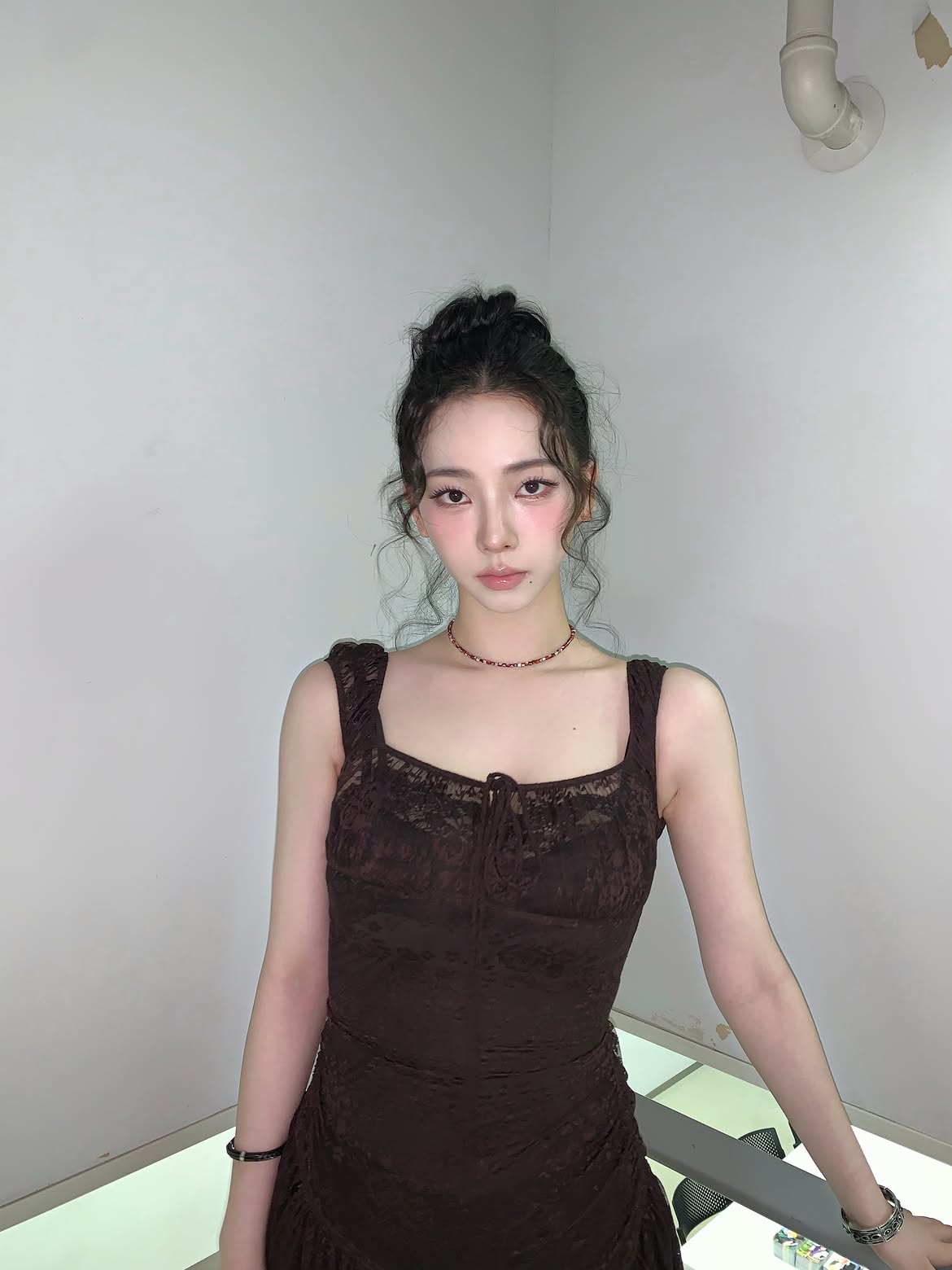 Karina in a black sheer dress crouching down, chest area - Instagram
