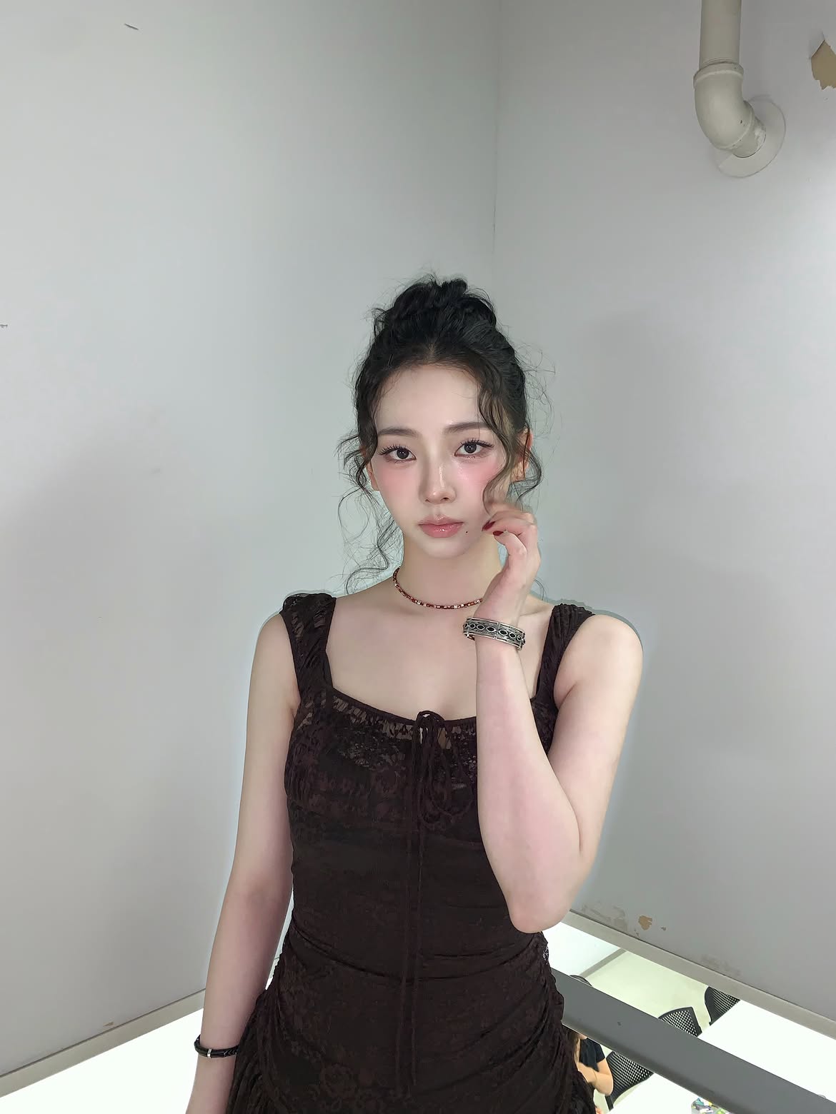 Karina in a black sheer dress crouching down, chest area - Instagram