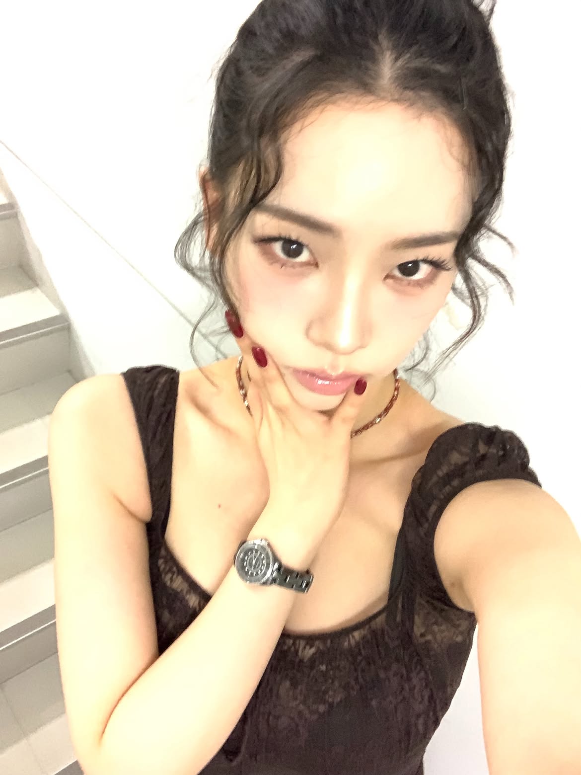 Karina in a black sheer dress crouching down, chest area - Instagram