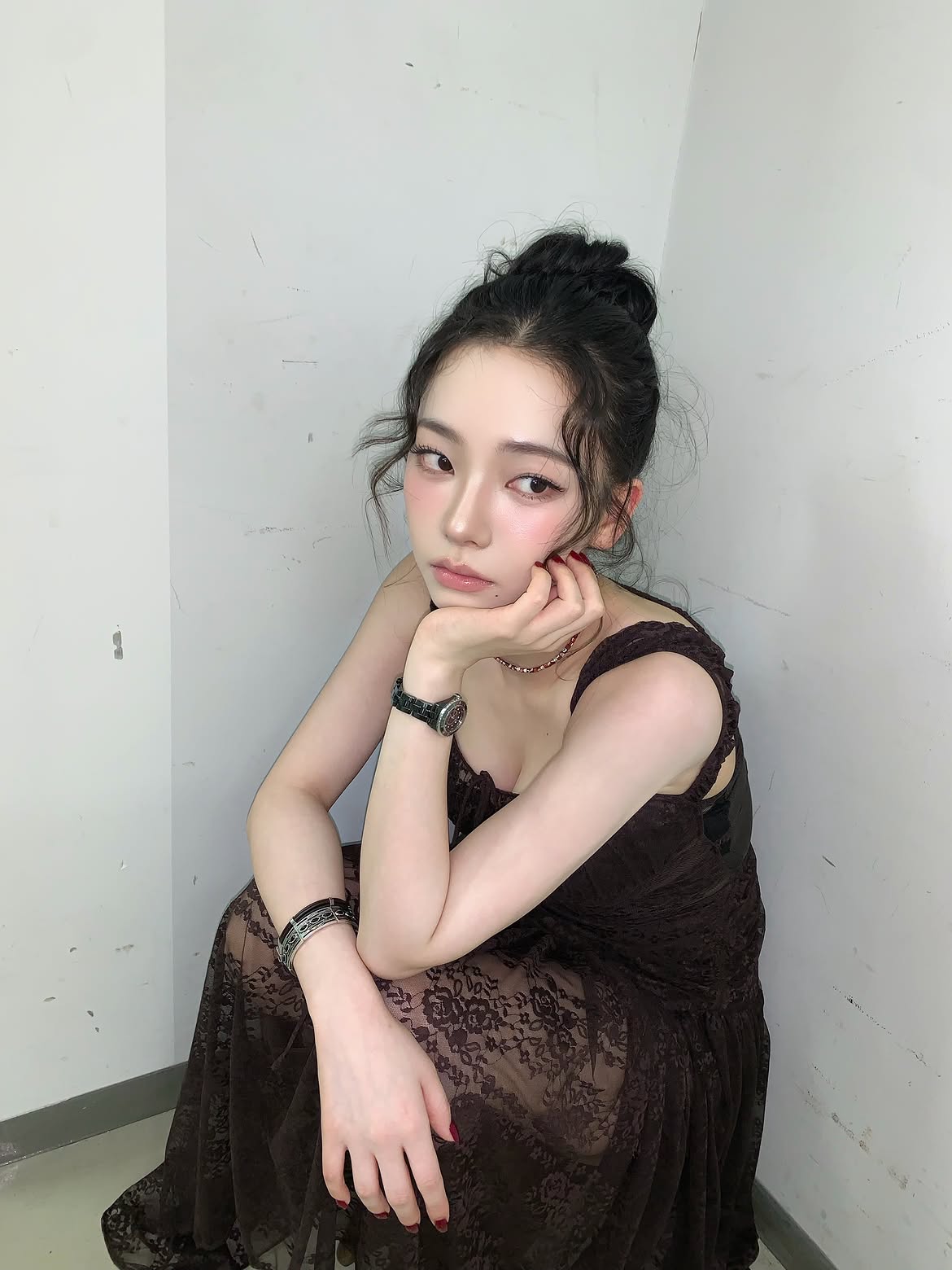 Karina in a black sheer dress crouching down, chest area - Instagram